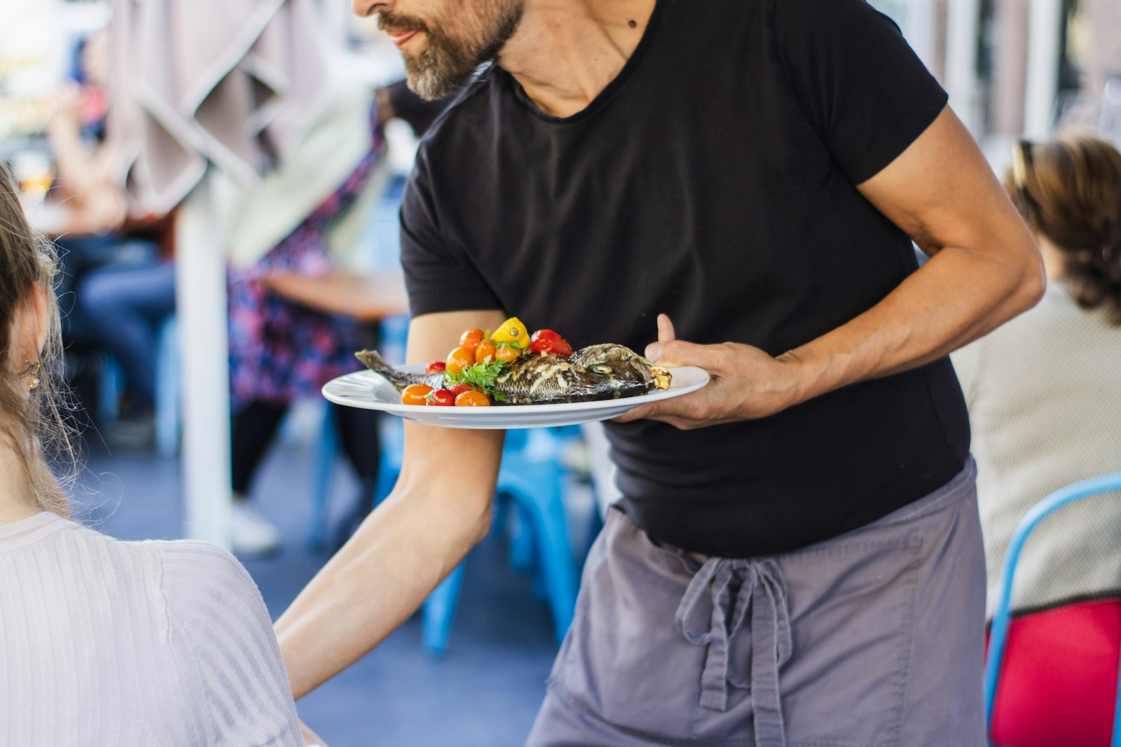 Ein Kellner serviert Gästen im Restaurant